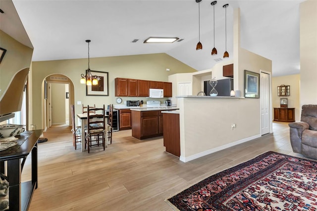 kitchen featuring hanging light fixtures, black fridge, a chandelier, vaulted ceiling, and light wood-type flooring