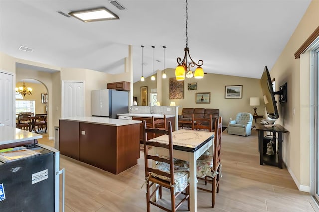 kitchen with an inviting chandelier, hanging light fixtures, lofted ceiling, and white refrigerator