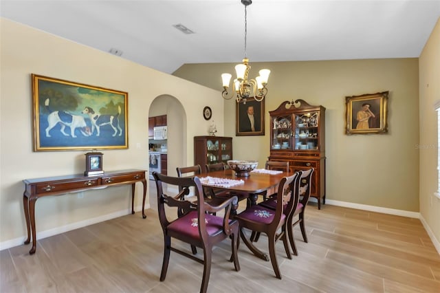 dining space featuring light wood-type flooring, lofted ceiling, and an inviting chandelier