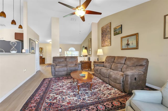 living room with ceiling fan, lofted ceiling, and light hardwood / wood-style flooring