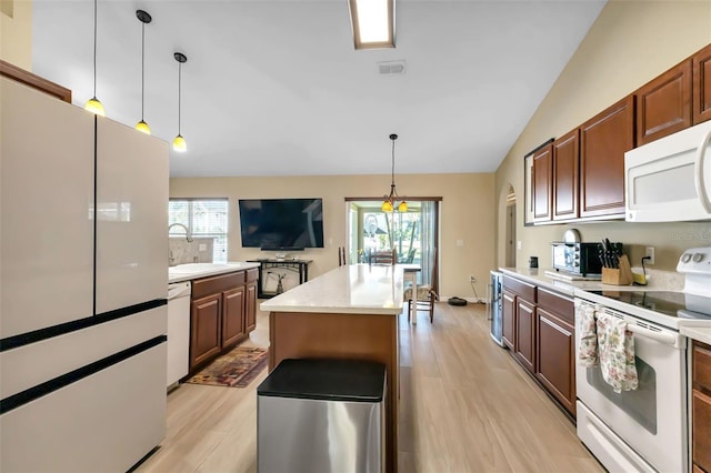 kitchen featuring sink, a center island, pendant lighting, lofted ceiling, and white appliances