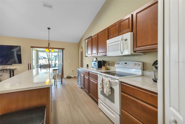 kitchen with a center island, lofted ceiling, white appliances, hanging light fixtures, and light wood-type flooring