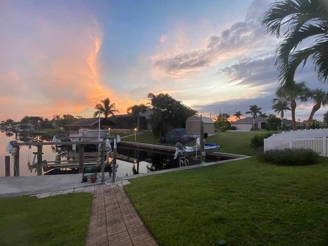 yard at dusk featuring a dock and a water view