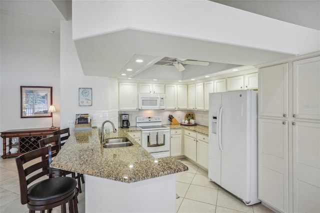 kitchen with kitchen peninsula, white appliances, ceiling fan, sink, and stone counters