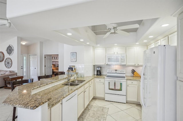 kitchen featuring kitchen peninsula, a kitchen breakfast bar, white appliances, and sink