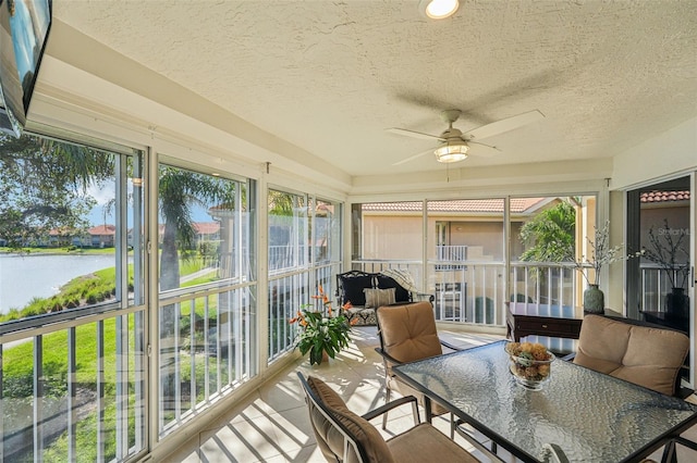 sunroom / solarium featuring a water view, plenty of natural light, and ceiling fan