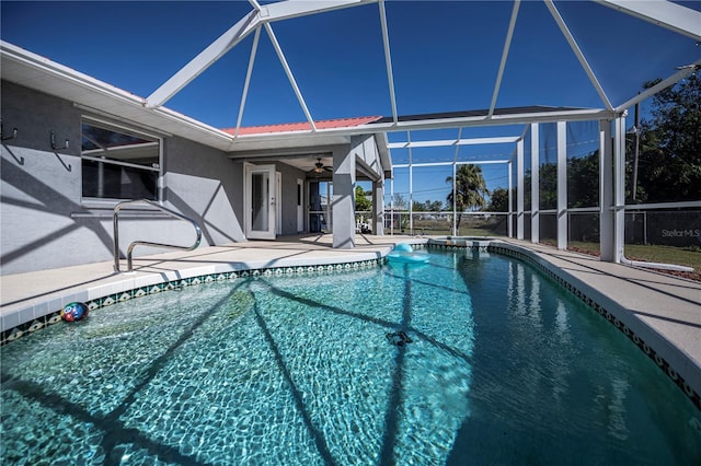 view of pool with glass enclosure, ceiling fan, and a patio