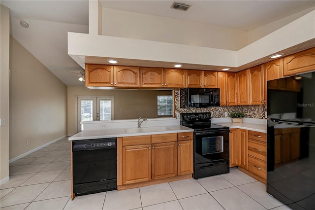 kitchen featuring sink, kitchen peninsula, vaulted ceiling, light tile patterned floors, and black appliances