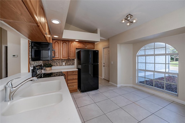 kitchen featuring decorative backsplash, sink, black appliances, light tile patterned floors, and lofted ceiling