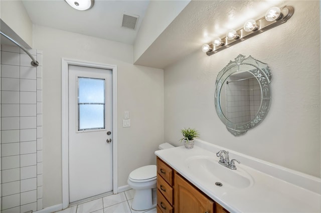 bathroom with tile patterned flooring, vanity, toilet, and a tile shower