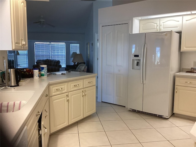 kitchen with light tile patterned floors, white cabinetry, white fridge with ice dispenser, and ceiling fan