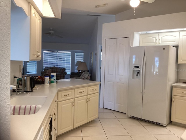 kitchen with white cabinetry, white fridge with ice dispenser, sink, lofted ceiling, and light tile patterned floors