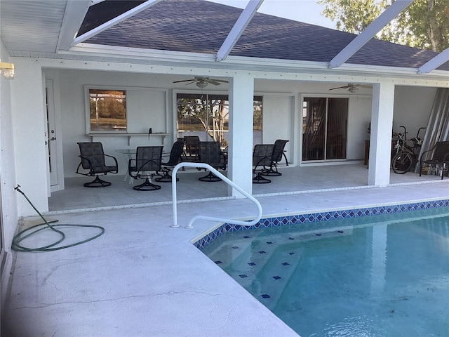 view of swimming pool featuring glass enclosure, ceiling fan, and a patio area