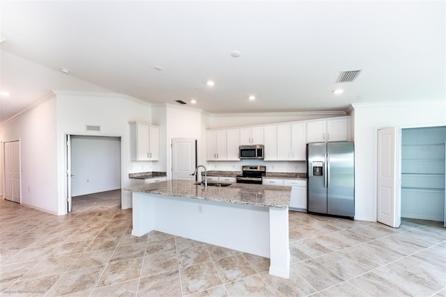 kitchen featuring white cabinetry, stainless steel appliances, light stone counters, lofted ceiling, and a center island with sink