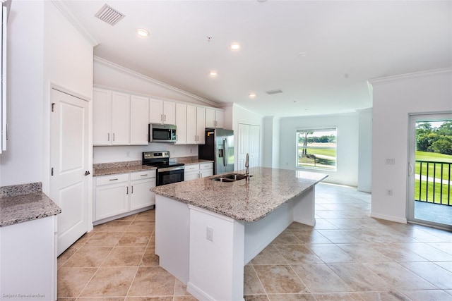 kitchen featuring appliances with stainless steel finishes, vaulted ceiling, a kitchen island with sink, sink, and white cabinets