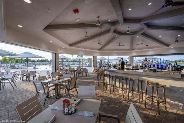 view of patio featuring ceiling fan, a water view, and an outdoor bar