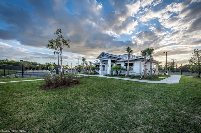 view of front of house with a front lawn and tennis court