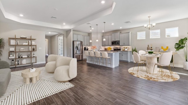16114 Highgate St, Port Charlotte, FL 33953 - living room with arched walkways, a chandelier, dark wood-type flooring, a tray ceiling, and recessed lighting