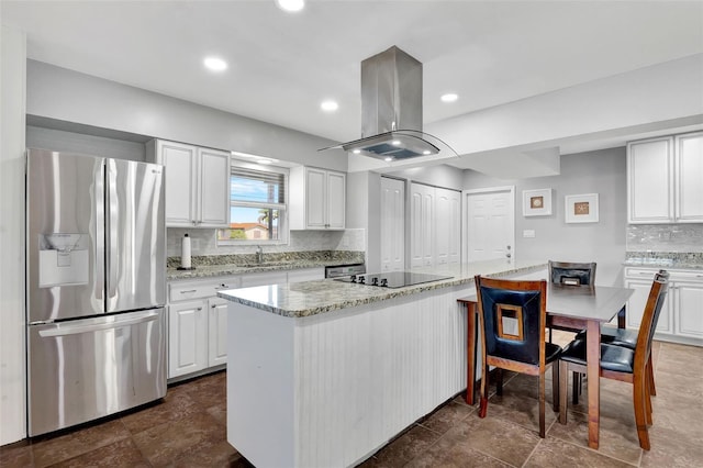 kitchen featuring white cabinets, stainless steel refrigerator with ice dispenser, island range hood, and black electric cooktop