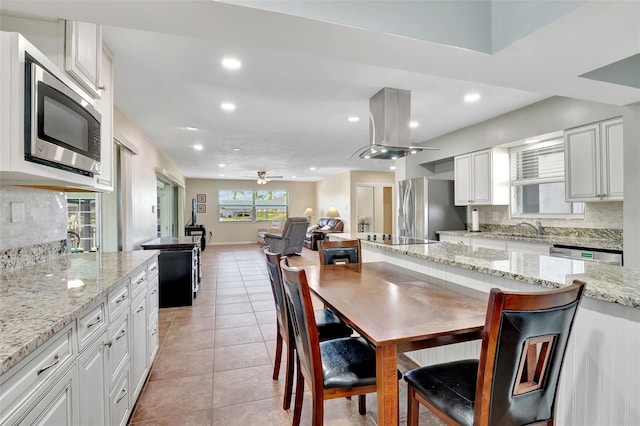 kitchen featuring backsplash, light stone countertops, white cabinets, and stainless steel appliances