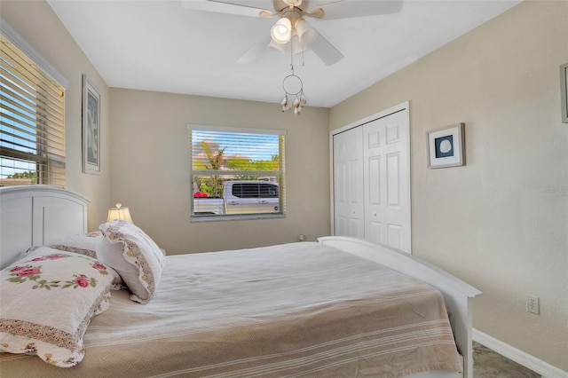 bedroom featuring multiple windows, a closet, carpet floors, and ceiling fan with notable chandelier