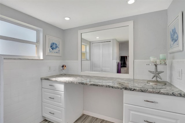 bathroom with vanity, wood-type flooring, and tile walls