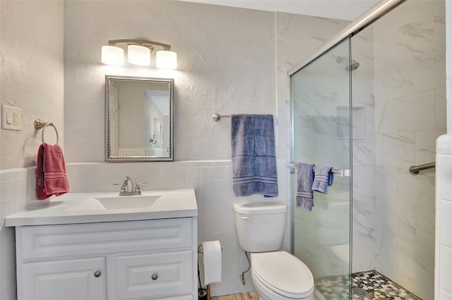 bathroom with tile walls, vanity, an enclosed shower, and toilet