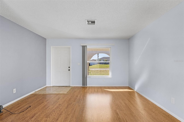 empty room featuring a textured ceiling and light wood-type flooring