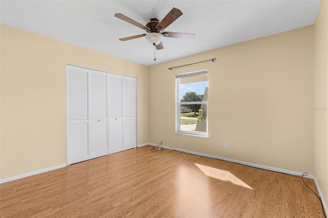 unfurnished bedroom featuring a closet, ceiling fan, light hardwood / wood-style flooring, and a textured ceiling