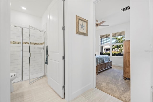 bathroom with toilet, ceiling fan, and a shower with shower door