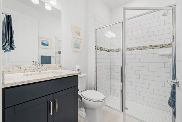 bathroom featuring vanity, a shower with shower door, and toilet