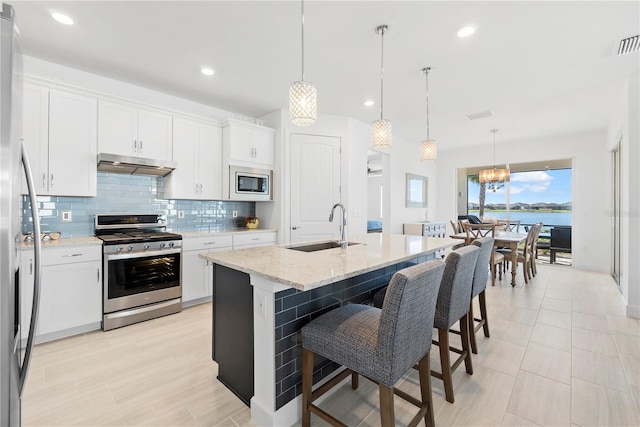 kitchen featuring a water view, hanging light fixtures, sink, white cabinetry, and stainless steel appliances