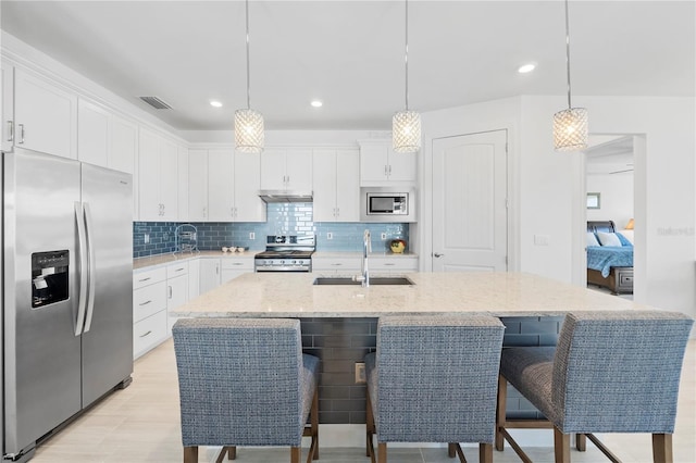 kitchen with white cabinets, stainless steel appliances, and a kitchen island with sink