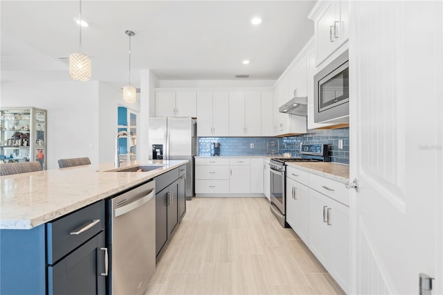 kitchen featuring white cabinetry, sink, an island with sink, decorative light fixtures, and appliances with stainless steel finishes