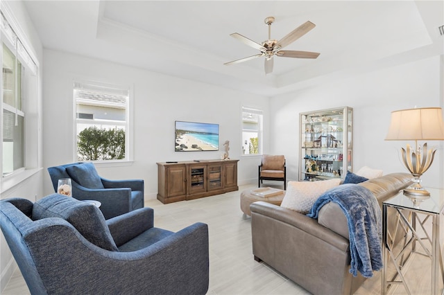 living room featuring light wood-type flooring, a raised ceiling, and ceiling fan