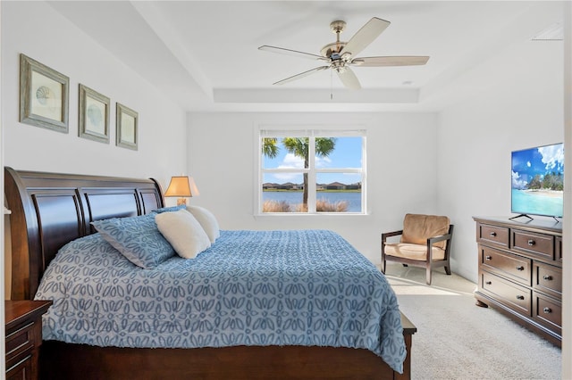 bedroom with a raised ceiling, ceiling fan, and light colored carpet