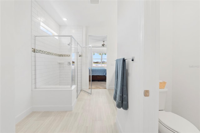 bathroom featuring ceiling fan, a shower with door, and toilet