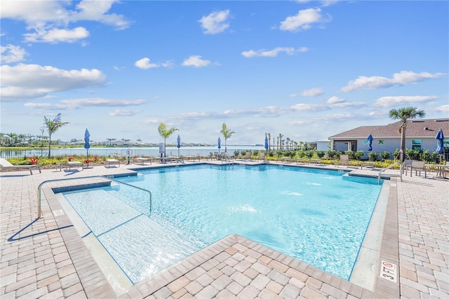 view of swimming pool with a patio area and a water view