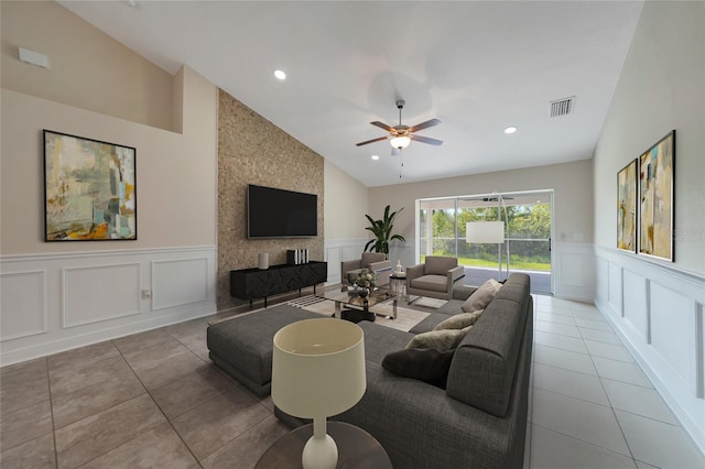 tiled living room with ceiling fan, a large fireplace, and vaulted ceiling