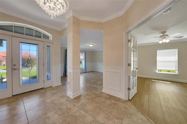 foyer entrance featuring ornate columns, crown molding, and ceiling fan with notable chandelier