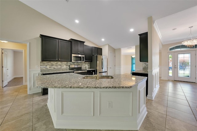 kitchen with light stone countertops, appliances with stainless steel finishes, light tile patterned floors, and lofted ceiling