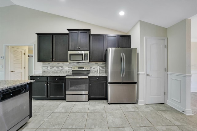 kitchen featuring light stone countertops, lofted ceiling, stainless steel appliances, and light tile patterned floors