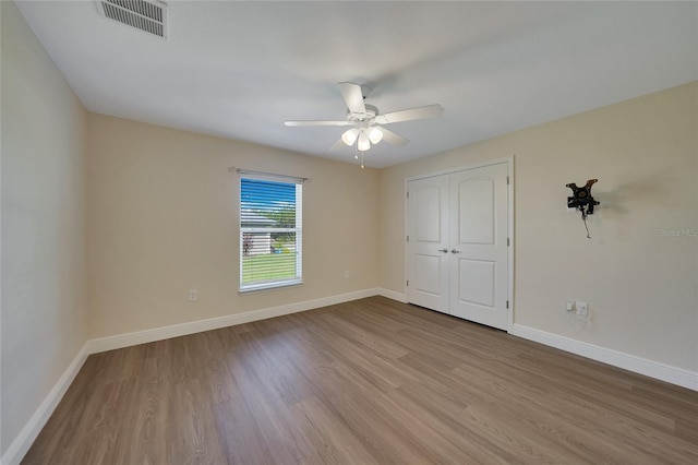 unfurnished bedroom featuring ceiling fan, a closet, and light wood-type flooring