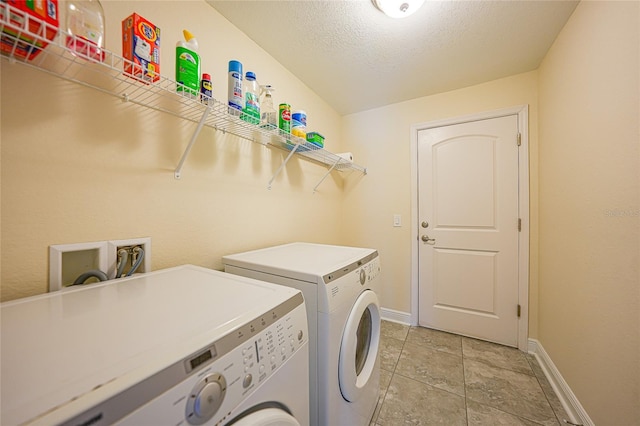 clothes washing area with separate washer and dryer, light tile patterned floors, and a textured ceiling