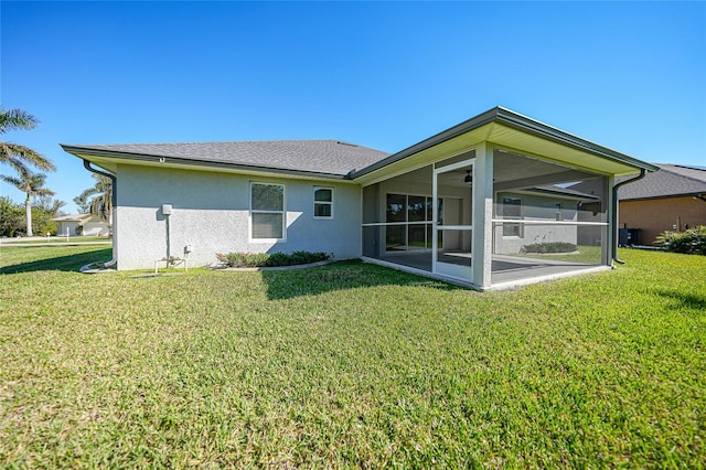 rear view of house featuring a lawn and a sunroom