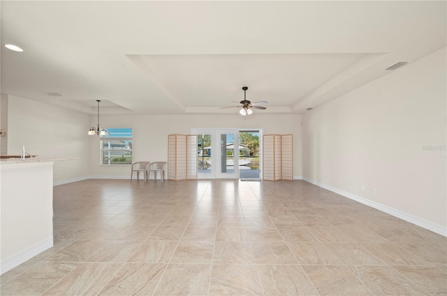 empty room with ceiling fan with notable chandelier, a raised ceiling, and sink