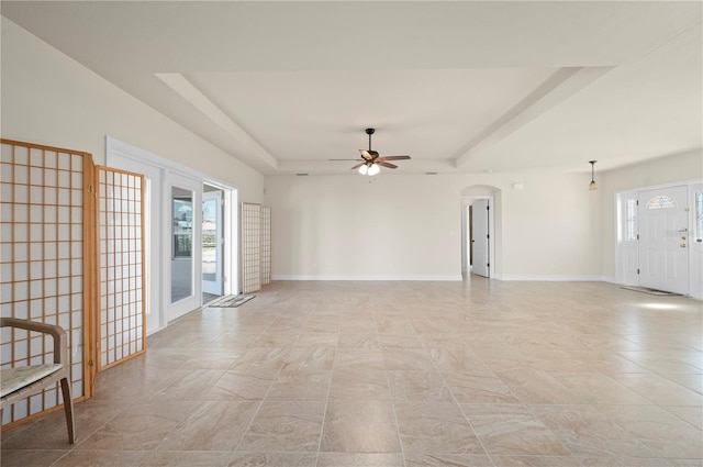 unfurnished room with ceiling fan and a raised ceiling