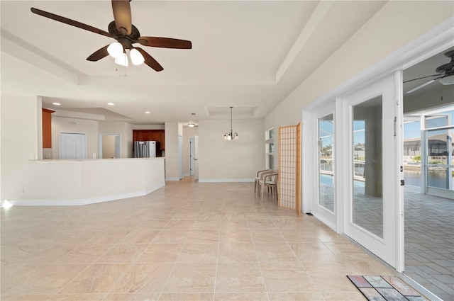 empty room featuring a raised ceiling, french doors, and ceiling fan with notable chandelier