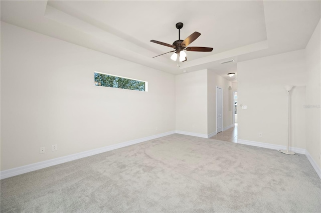 carpeted spare room featuring a raised ceiling and ceiling fan