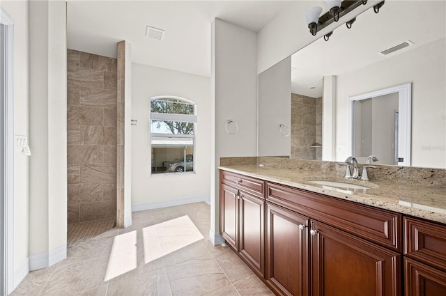 bathroom with a tile shower, vanity, and tile patterned floors